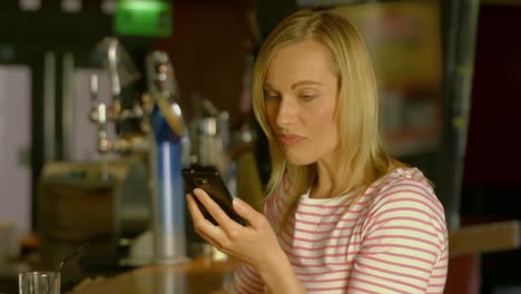 woman using her phone at the bar