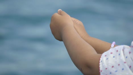 child's hands with bracelet by the sea