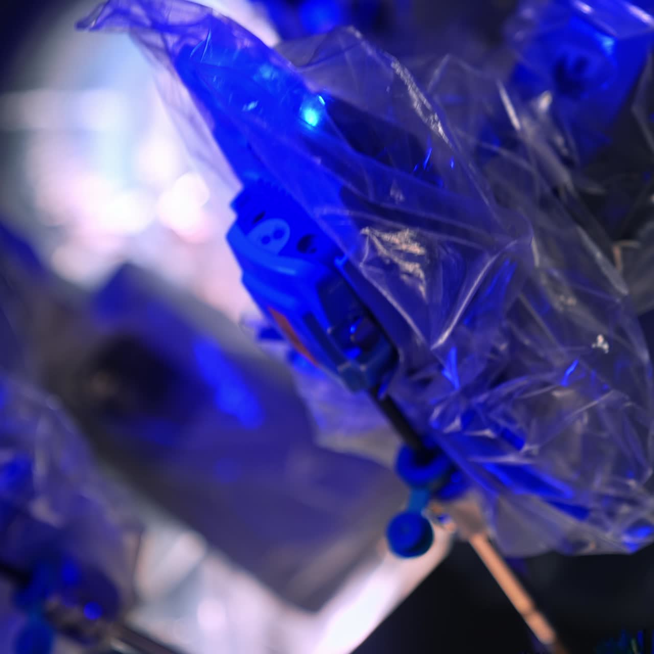 Movement of robotic arms coated with plastic. Da Vinci futuristic equipment working in dark surgery room. Close up. Blurred backdrop