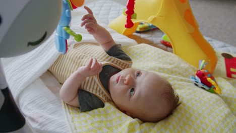 adorable blue eyed, eight week old baby smiles while playing under her arc gym toy