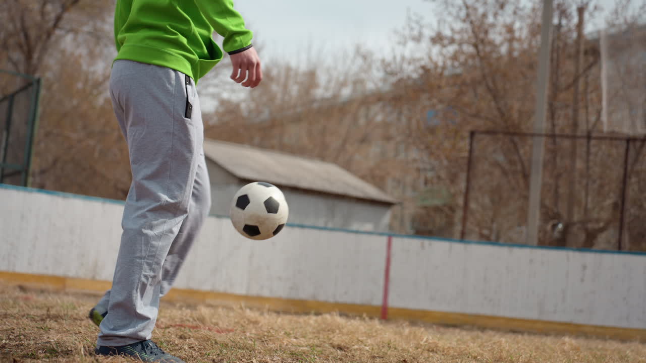 hombre practicando habilidades de fútbol al aire libre, hombre realizando maniobras precisas con los pies con un balón de fútbol al aire libre, primer plano de un atleta masculino ejecutando malabarismos de fútbol precisos en un entorno de patio trasero arenoso