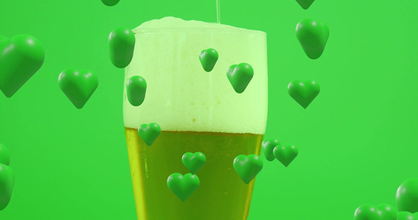 Pour stream making foam on beer glass staying centered while green hearts drifting creating focus