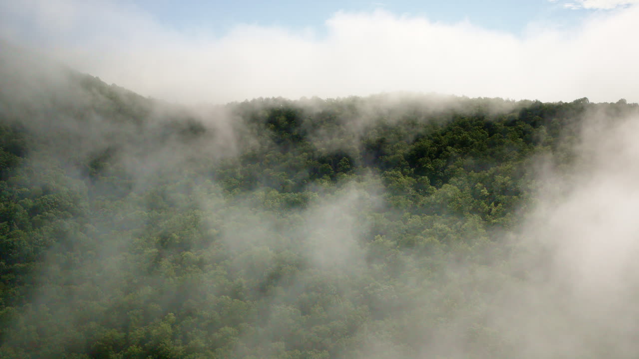 Aerial drone pushes gently into a fog-laden mountain range