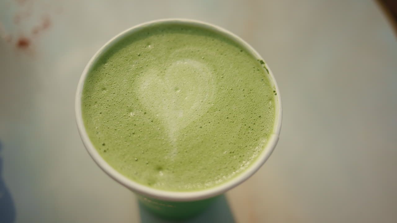 Vista de cima de um latte de matcha verde cremoso com textura de espuma.