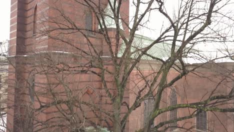 Cinematic-movement-showcasing-old-church-building-in-background,-taken-from-behind-a-tree-