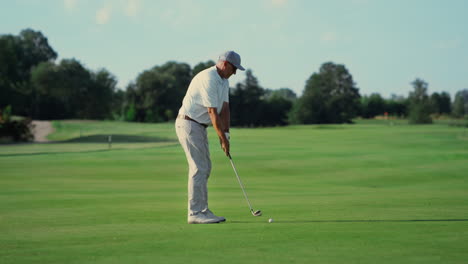 old man play golf on grass fairway. pro player swing club hitting ball outside.