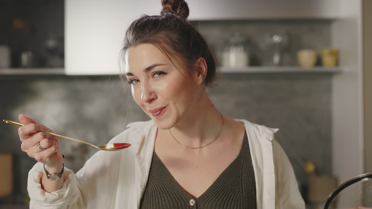 Woman tasting food while cooking in a kitchen