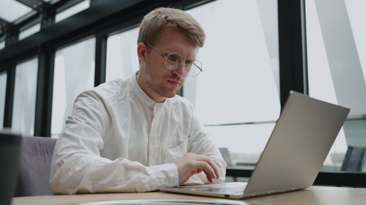 Concentrated young man typing on laptop in cafe