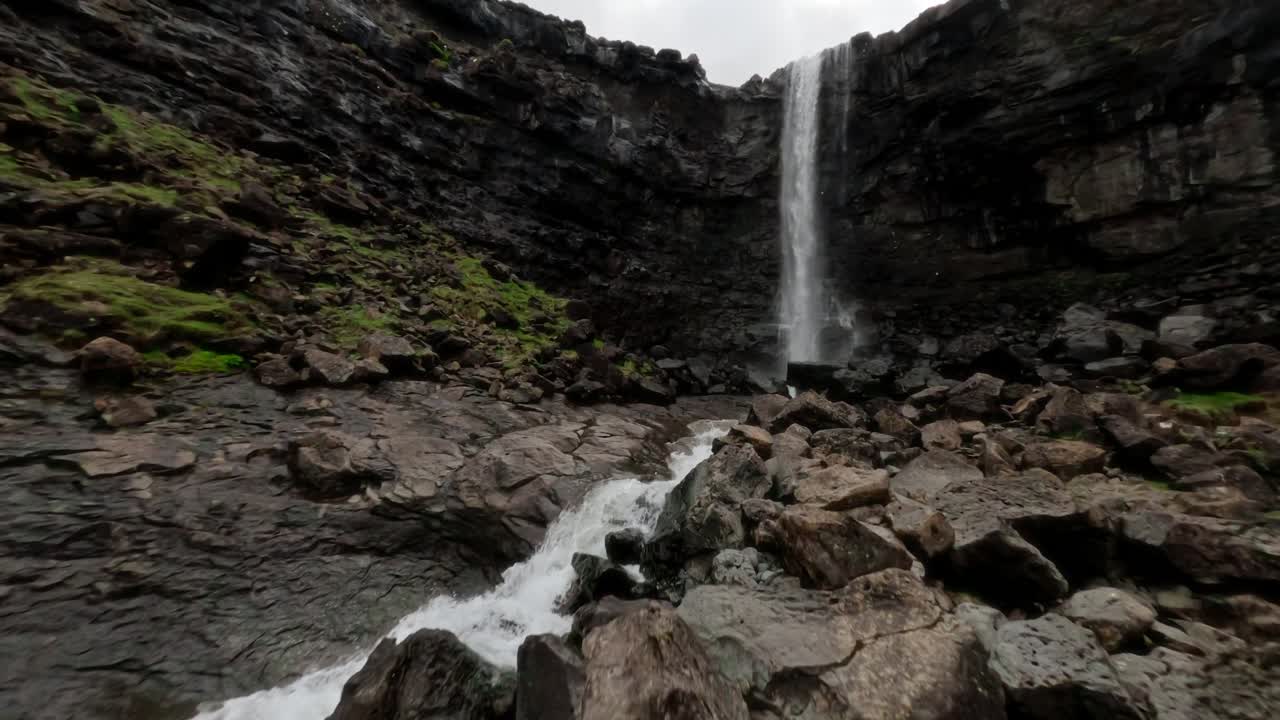 una vista aérea panorámica de una alta cascada en un cañón rocoso en las islas feroe