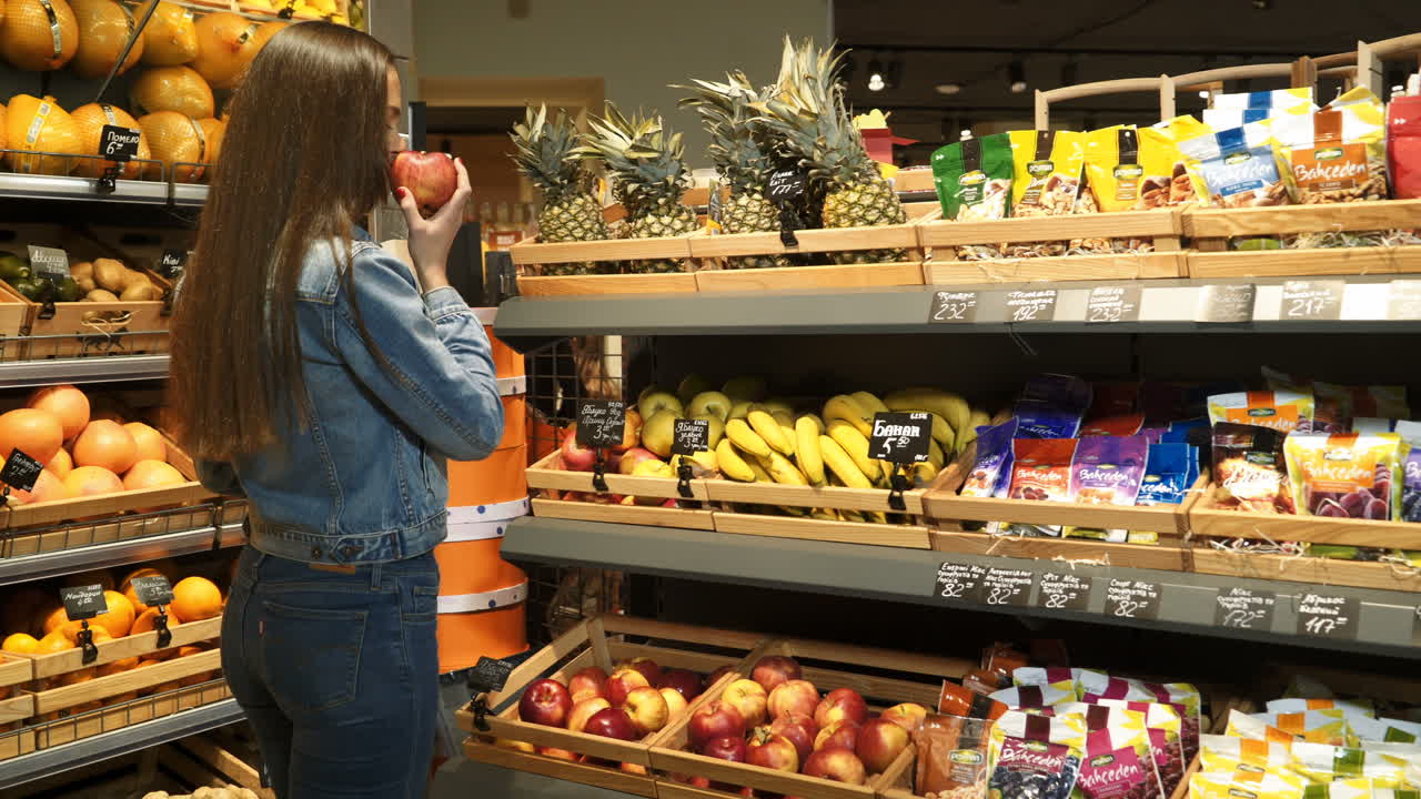 Beautiful girl buying vegetables in organic shop at supermarket. Woman with a paper bag with fruit. Lifestyle. Healthy eating. Raw food.