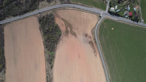 Top-Down-Aerial-View-of-Farming-Field-and-Tractor-Preparing-Land-For-Another-Seeding-Season,-High-Angle-Drone-Shot