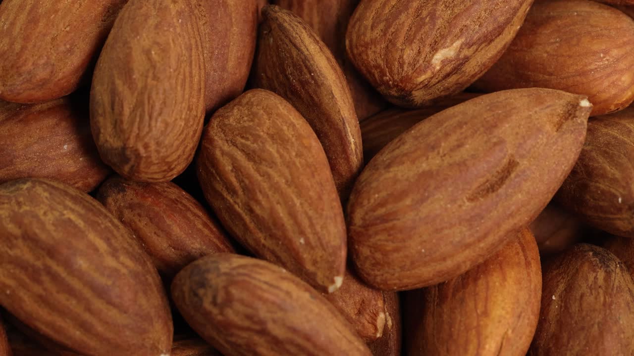 Detailed macro view of almonds with rich textures and warm lighting, highlighting their natural brown hues and surface details