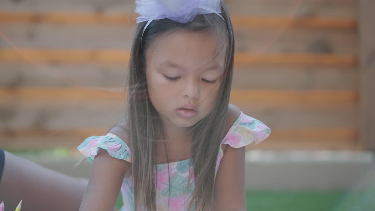 엄마와 어린 딸이 뒷마당에서 담요 위에 앉아 함께 그림을 그리고 있습니다. 야외 장면은 평화로운 가족 순간을 포착하여 창의성과 유대를 촉진합니다.