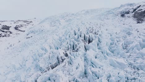 aerial landscape view over ice formations in falljokull glacier covered in snow, iceland, at dusk