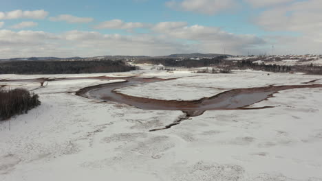 aerial view flying over a frozen, snow covered wetland marsh along the atlantic coast