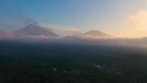 Espectacular-Vista-Aérea-De-2-Volcanes-De-Una-Hermosa-Cordillera-Rodeada-De-Nubes-Durante-El-Amanecer-En-El-Fondo