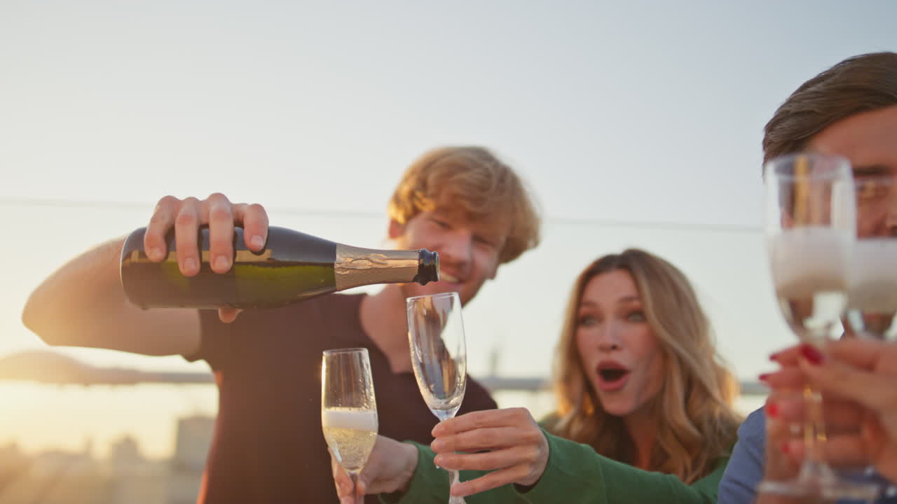 Colleghi in festa che versano vino nei calici godendosi l'incontro su una terrazza, primo piano.