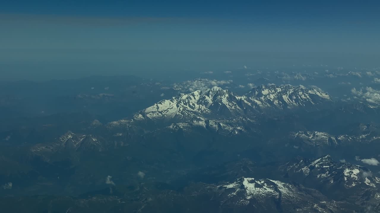 An elevated aerial view of the Alps Mountains at sunset in a summer day. Footage taken from a jet cockpit.