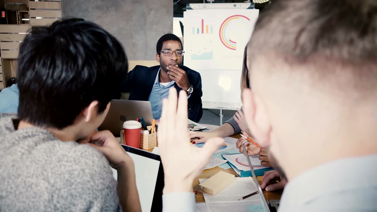 아프리카계 미국인 사업가가 사무실 회의를 이끌고, 젊은 다민족 그룹이 비즈니스 코퍼레이션 전략을 개발합니다.