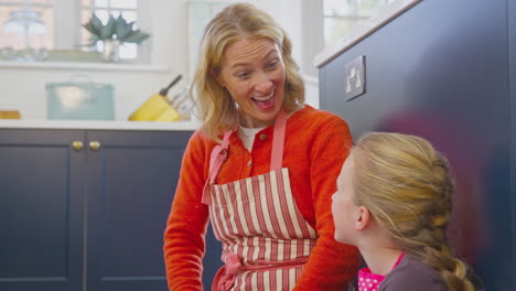 Grandmother-And-Granddaughter-Waiting-For-Cupcakes-To-Bake-In-Kitchen-At-Home