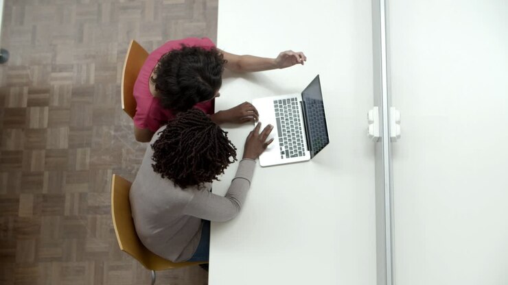 Vue de dessus de femmes regardant un ordinateur portable à la bibliothèque