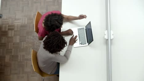 Vista-Superior-De-Las-Mujeres-Que-Miran-La-Computadora-Portátil-En-La-Biblioteca