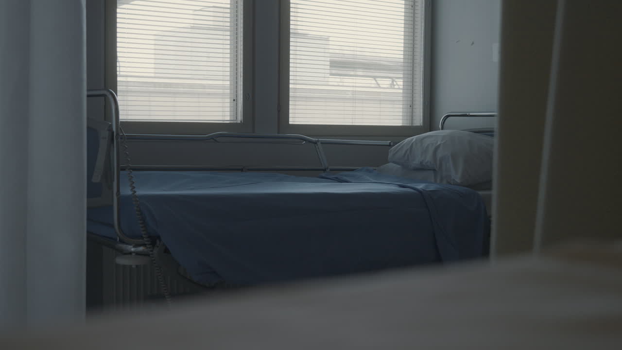 움직이는 커튼 뒤에 있는 빈 병실 침대