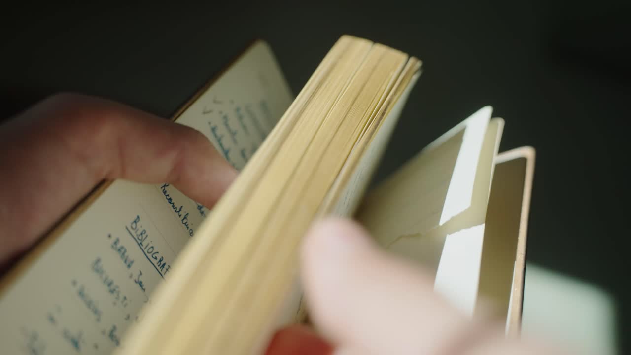 Hands flip pages of an old book, light through window, peaceful mood