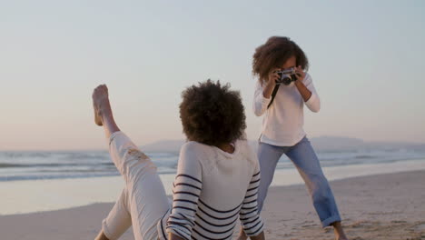 Back-View-Of-An-Woman-Siitng-And-Posing-On-The-Beach-While-Her-Cute-Daughter-Taking-Photos
