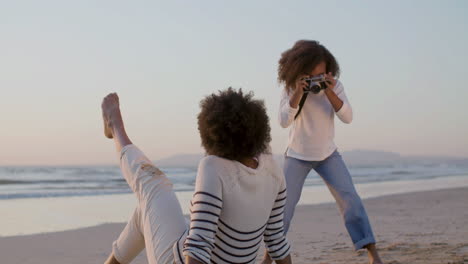 Rückansicht-Einer-Frau,-Die-Am-Strand-Sitzt-Und-Posiert,-Während-Ihre-Süße-Tochter-Fotos-Macht