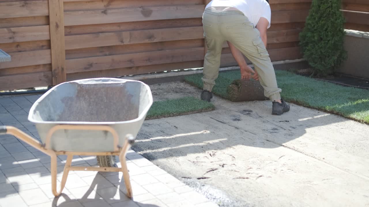 hombre colocando césped en el jardín del patio trasero para la instalación de césped y proyecto de jardinería, centrado en la mejora del hogar y el mantenimiento al aire libre para un césped fresco y verde en un patio residencial