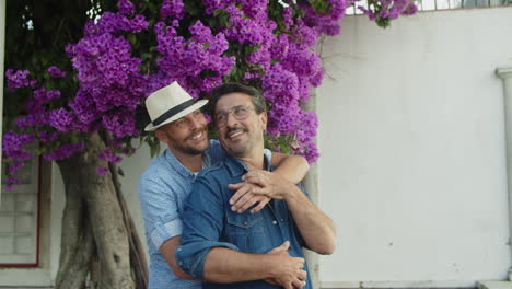 hombre homosexual feliz con sombrero abrazando a su novio desde atrás