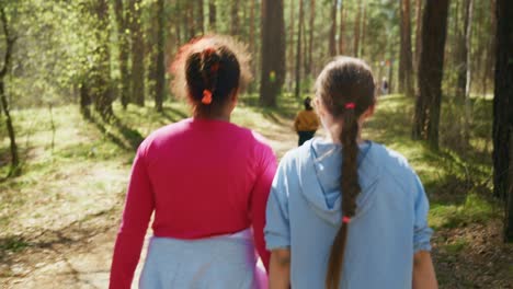 children walking hand-in-hand in a forest path