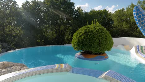 mosaic-tiled jacuzzi with a beautiful pool and tree in the background