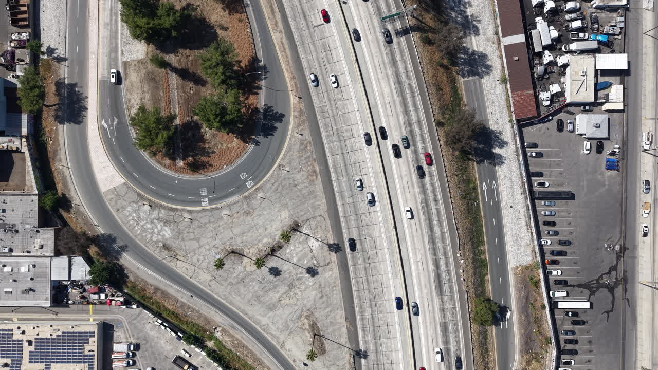 Filmato aereo cinematografico diurno con drone, catturato da una prospettiva a volo d'uccello dall'alto, sopra l'Autostrada 5 vicino a uno svincolo d'uscita a Los Angeles.
