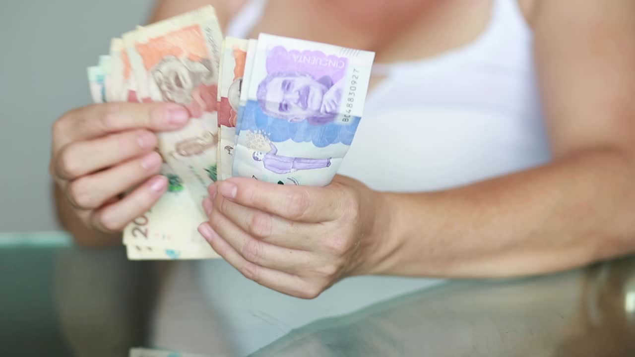 mujer contando billetes en moneda colombiana, pago recibido