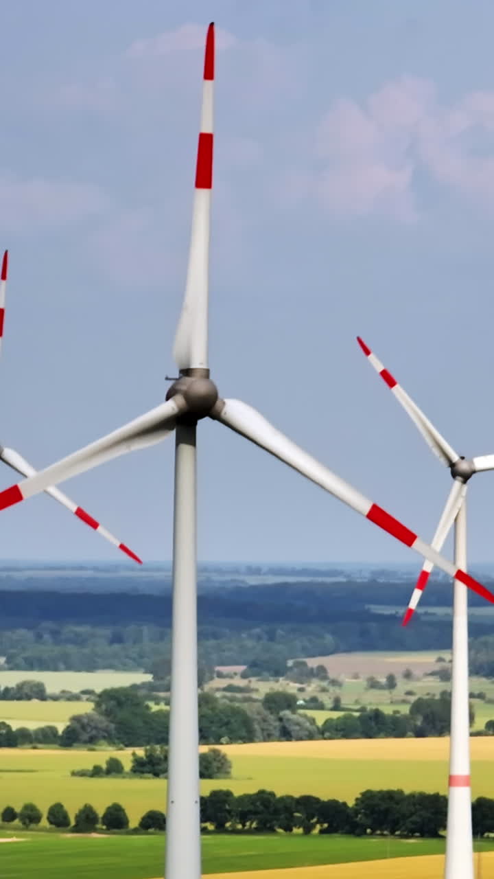 Portrait aerial view orbiting a wind power generator, sunny, summer day in Europe