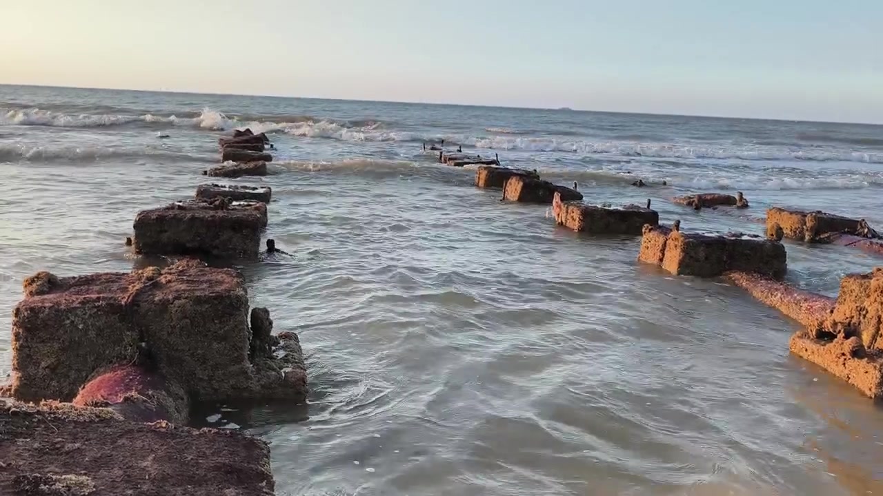 Mořské vlny tříštící se o zříceniny starého betonového mola