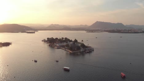 Imágenes-Aéreas-De-Drones-De-4k-Del-Palacio-Del-Lago-Taj-En-El-Lago-Pichola-Durante-La-Puesta-De-Sol-Cerca-De-La-Ciudad-De-Udaipur,-India