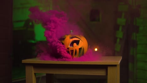 purple pink smoke coming out of the pumpkin in front of green spooky background | slowmotion