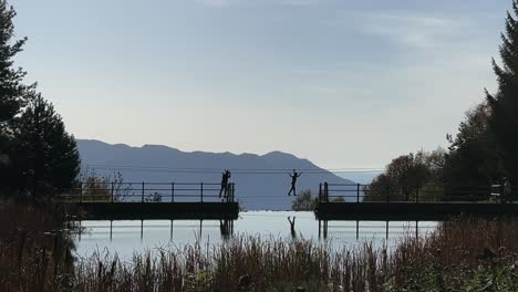 Unrecognizable-people-crossing-water-on-Tibetan-bridge-of-rope-adventure-park