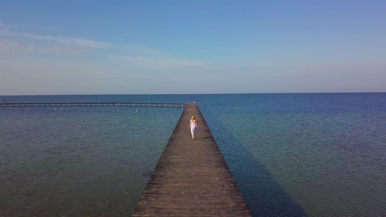 A girl walks on a wooden pier near the sea 02