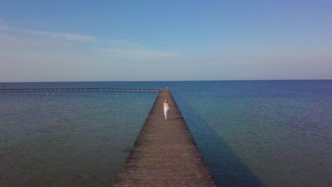 a girl walks on a wooden pier near the sea 02