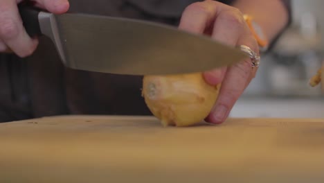 Closeup-of-a-woman-taking-a-knife-to-cut-an-onion-on-a-chopping-board