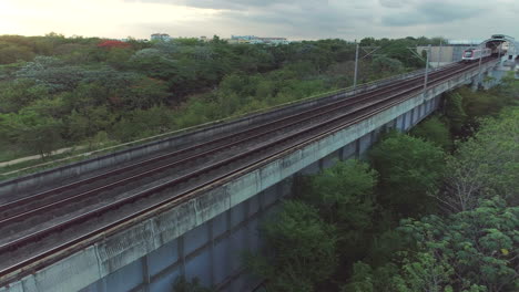 aerial view of a train on an elevated track crossing a lush green landscape