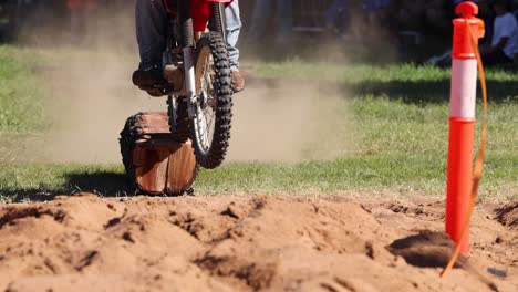 motorcyclist jumping over logs in a dirt track