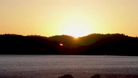 Time-lapse-bright-orange-sunset-sun-sets-behind-the-mountains