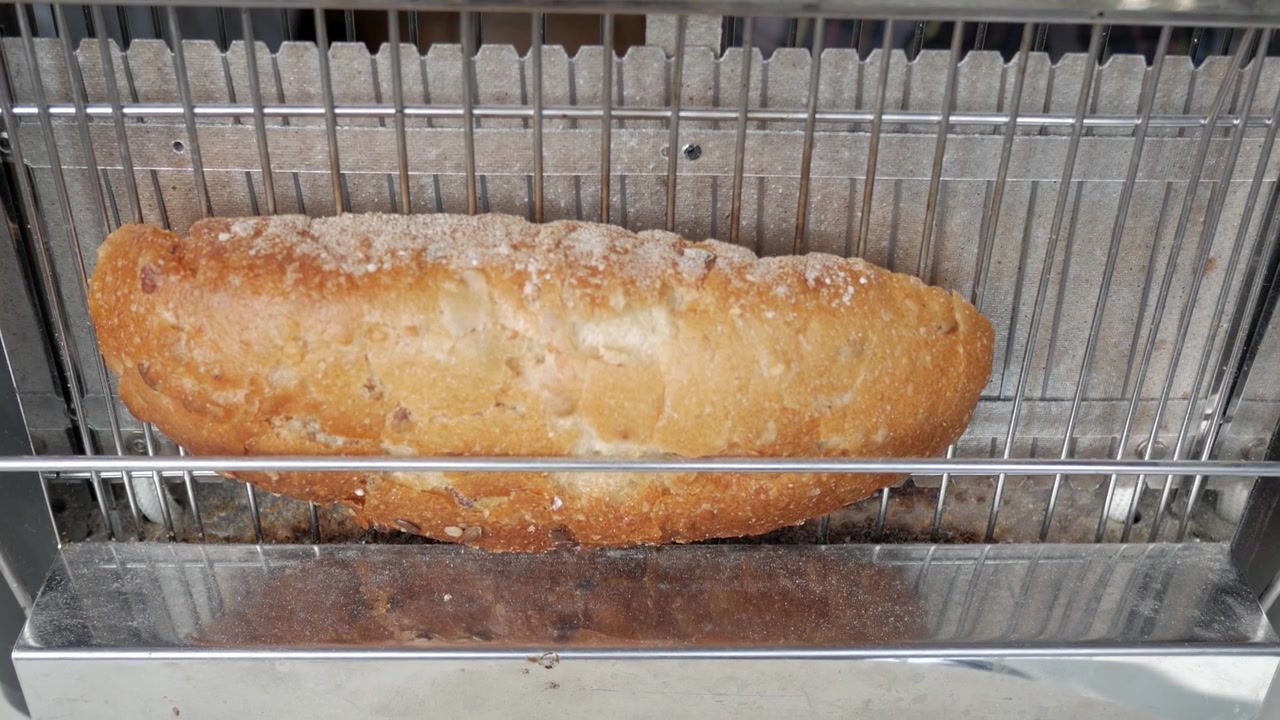 Slice of bread is placed on vertical electric toaster seen from close up.