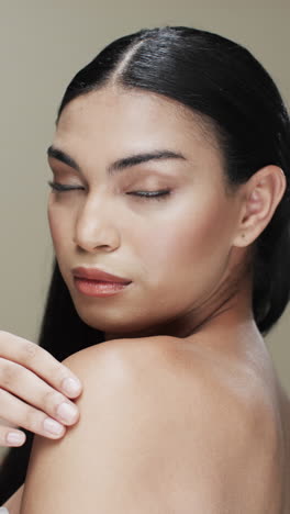 vertical video of biracial woman with black hair, make up looking at camera, copy space, slow motion