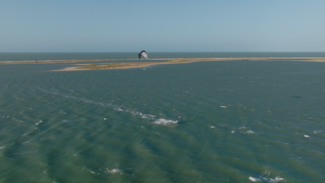 Kitesurfer glides on turquoise lagoon at Ilha do Guajiru, Ceará, Brazil, on windy day